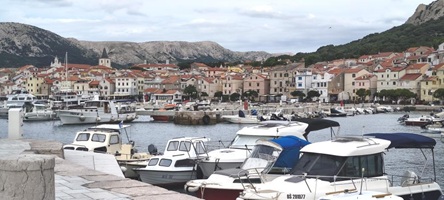Blick auf den Hafen von Baska mit mehreren Booten und einer malerischen Stadtansicht im Hintergrund.
